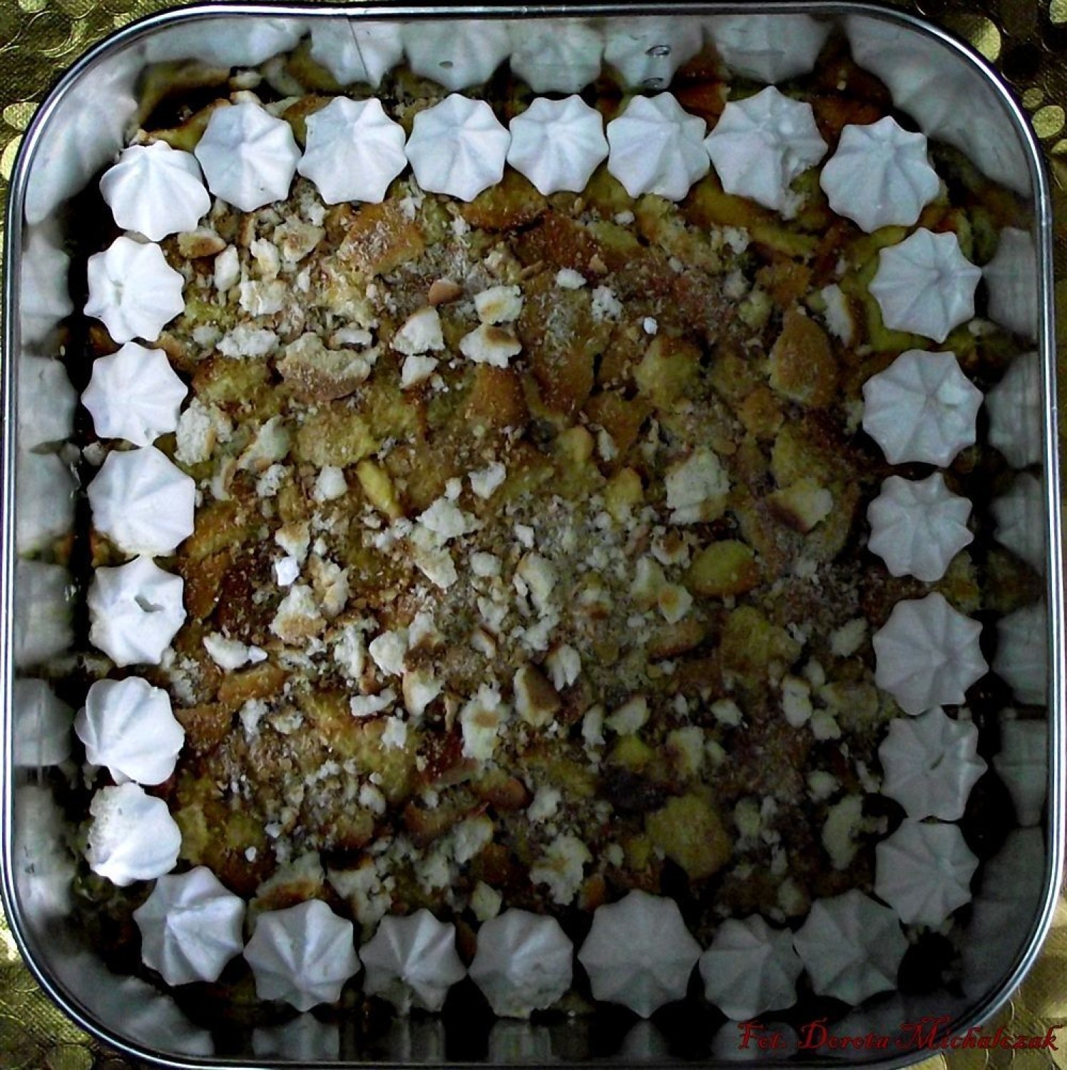Dno kwadratowej tortownicy (24 cm) wyłożyć grubo pokruszonymi biszkoptami, zwilżyć ponczem (sok z cytryny, kieliszek wódki, wodę i cukier dobrze wymieszać), boki tortownicy obłożyć bezami